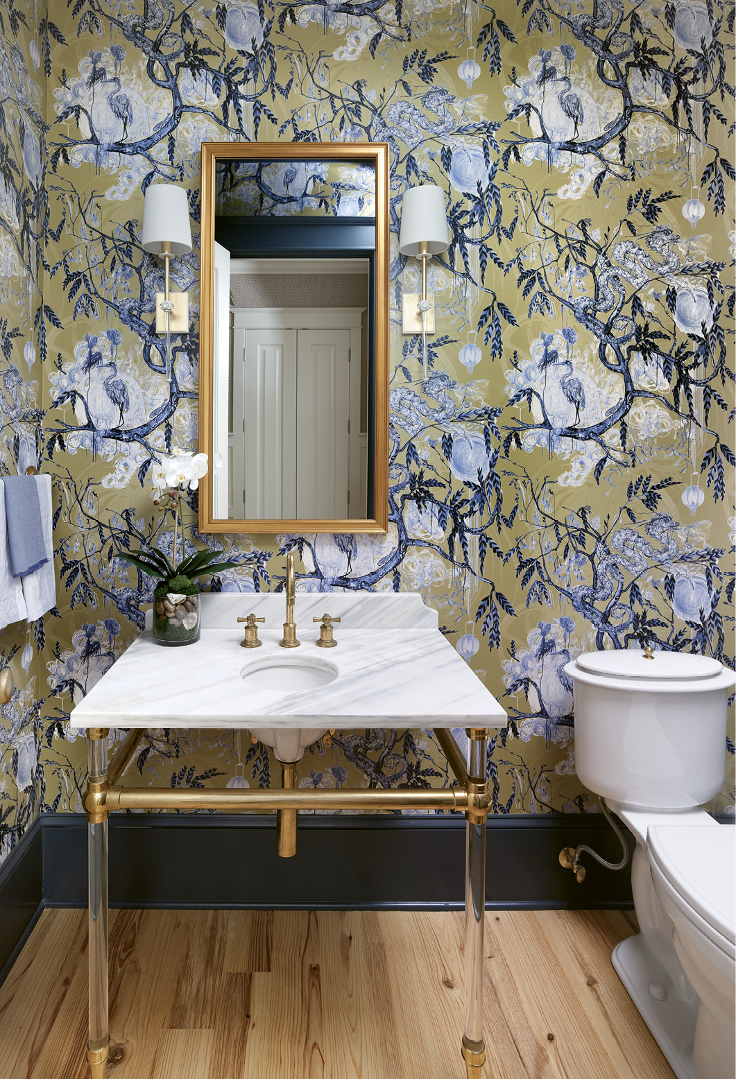 Brass and Lucite fixtures combined with Lowcountry-inspired wallpaper turn the powder room into an elegant jewel box.