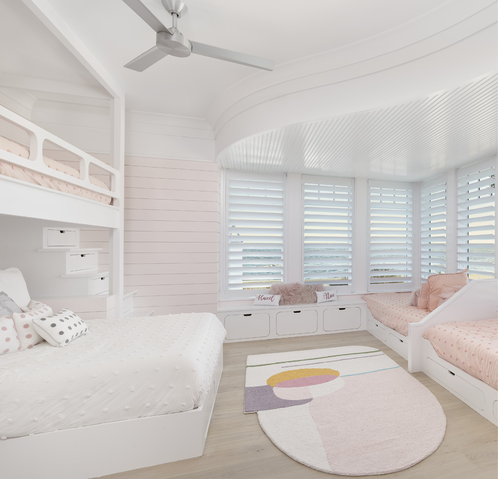 The girls’ bunk room repeats the serpentine soffits found in the downstairs wine room. It also features cutout details in the bunk railings and stairs with built-in storage in the risers. A queen bed allows the option of an adult joining in the sleepover.